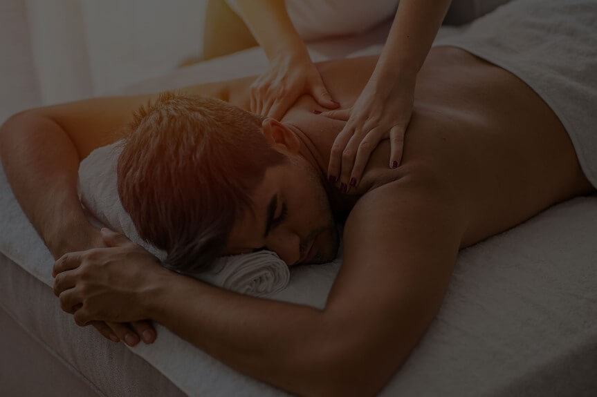 A person lying face down on a massage table receiving a back massage.